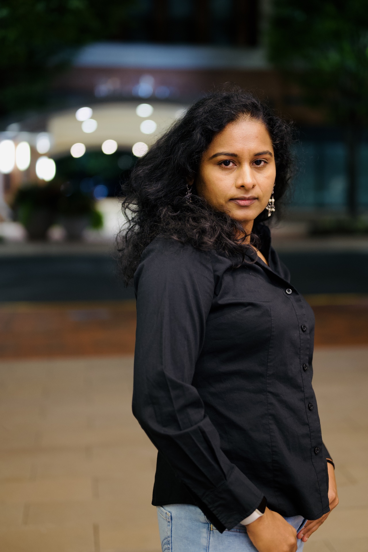 Evening portrait in a black shirt with city bokeh behind — Vetri Frames, the DMV