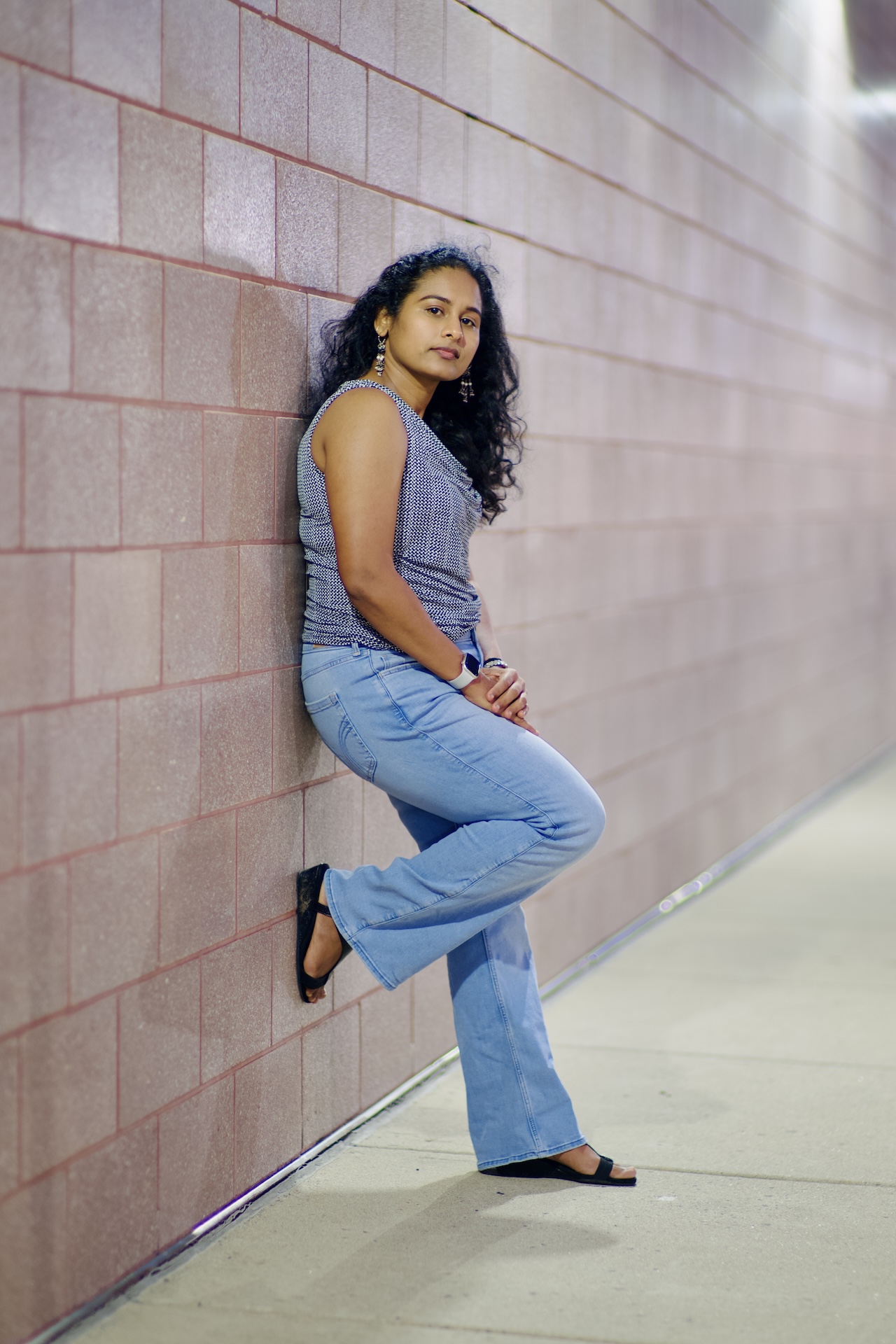 Leaning against a rose brick wall in denim and a printed top — Virginia fashion portrait
