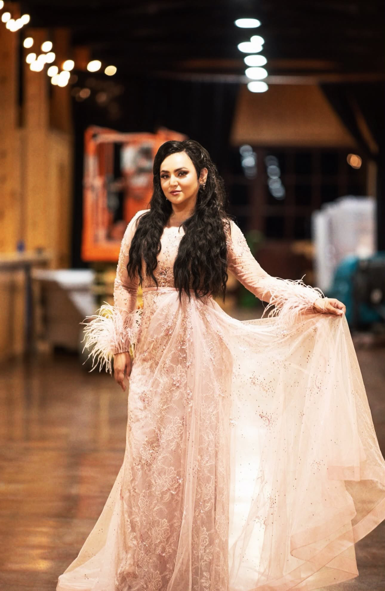 Feather-cuffed blush tulle gown sweeping across a warehouse floor — the DMV fashion photography