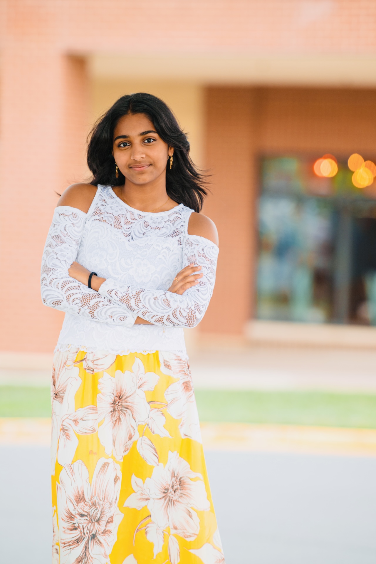 Senior portrait in white lace and a yellow floral skirt against a warm brick plaza — Vetri Frames, Virginia